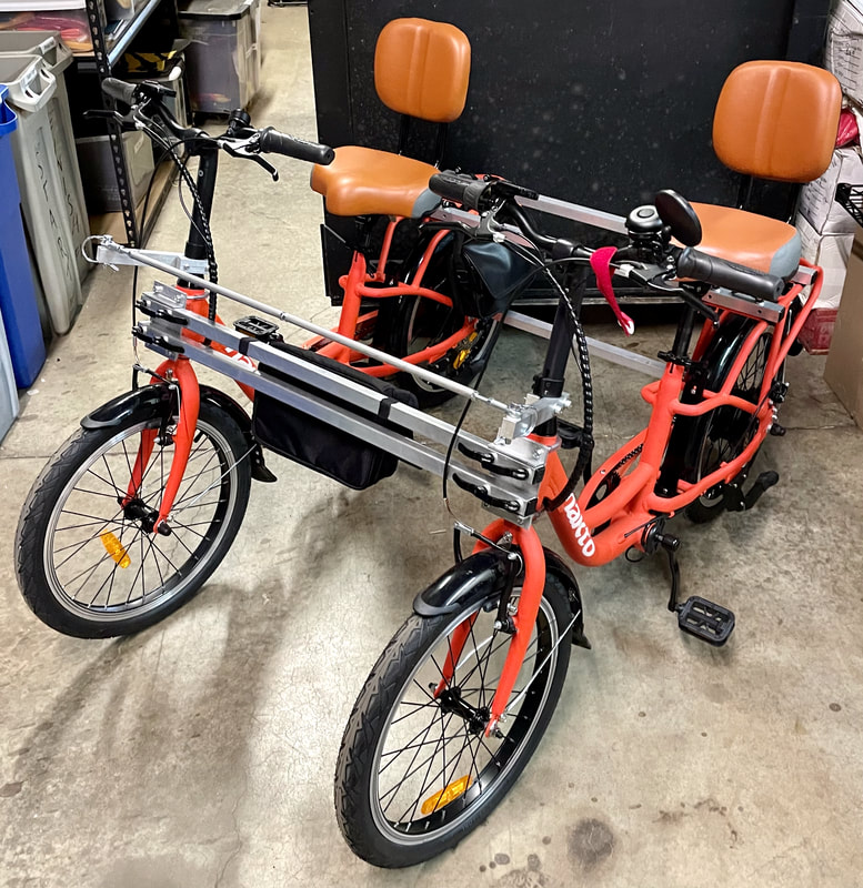 Citrus Red Nakto Pony 250W ebikes connected into a side-by-side tandem for adaptive cyclists. Great alternative to an adult trike.