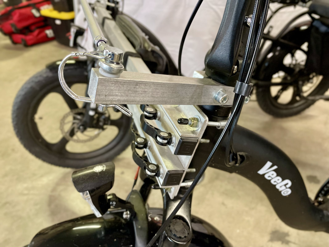 Close up of the front steering arm and beams connecting 2 Veego 750W eBikes together for a modern tandem quad bike.